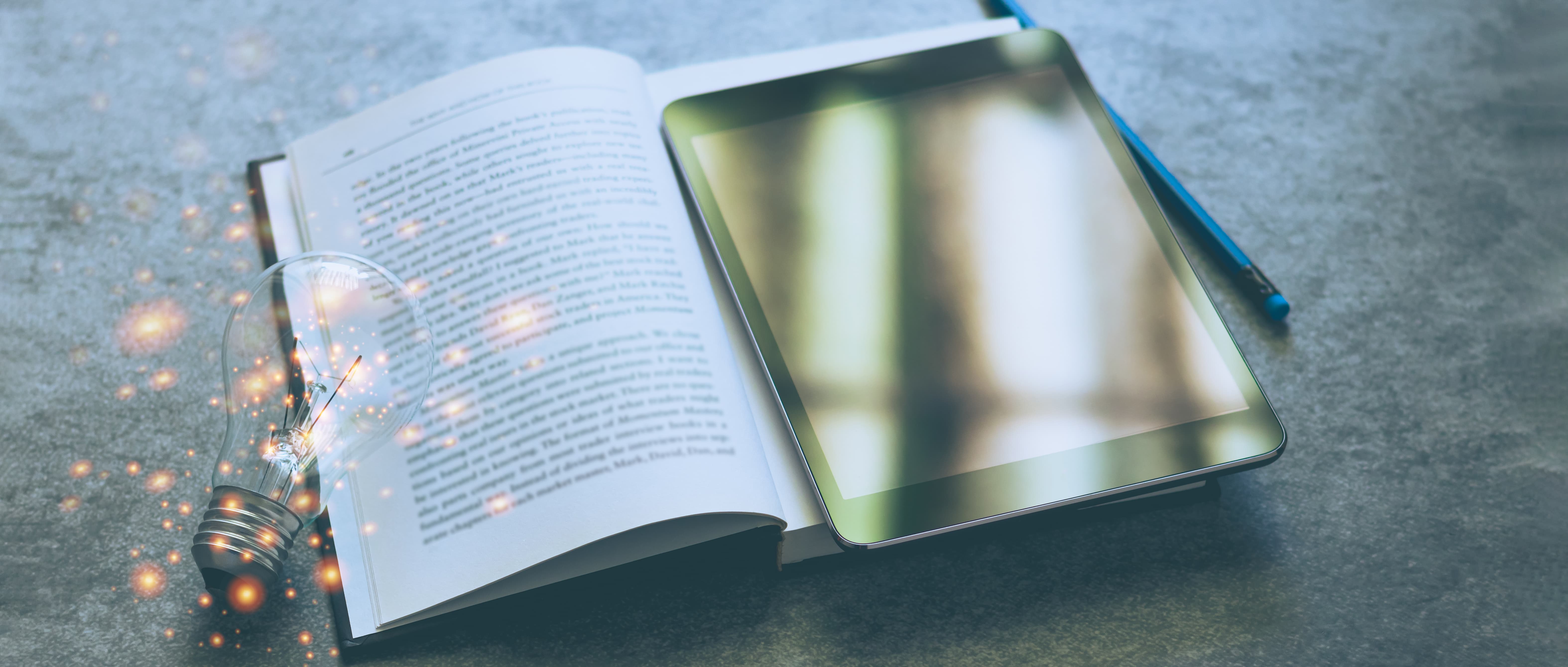 A book laying open with an ipad on top of half of the book pages