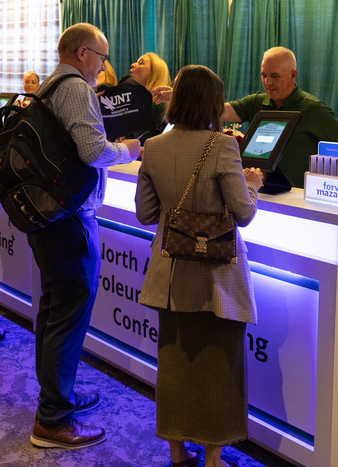 Event staff assisting attendees at a professional conference registration table.