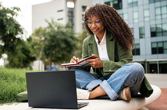 Smiling professional holding books on a college campus.