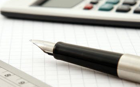 pen on a notepad next to an electric calculator